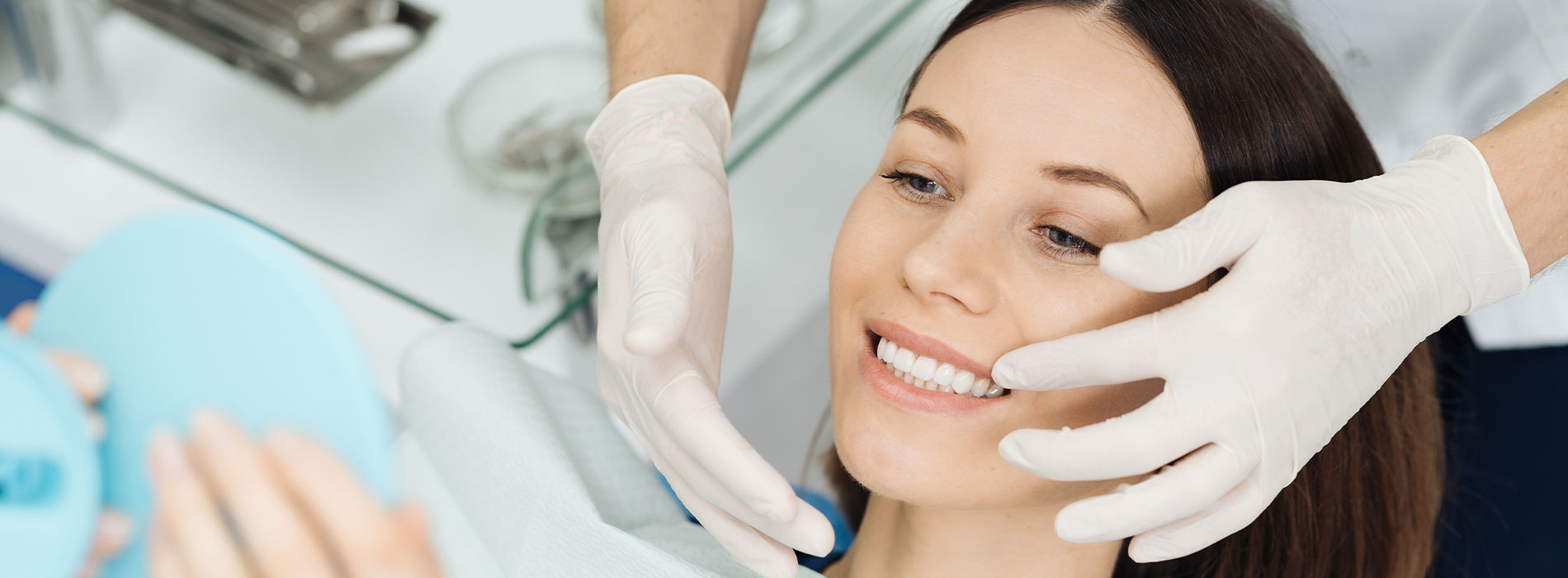 The image depicts a woman receiving a facial treatment with a visible blue mask on her face while being attended by a professional wearing gloves and a white apron, set against a clean, clinical background.