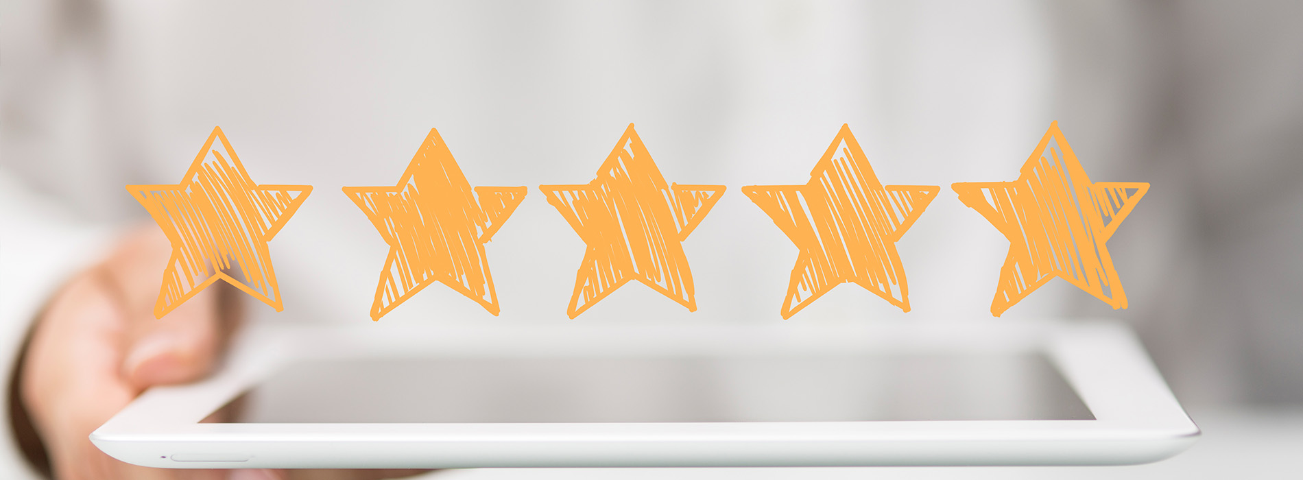 The image shows a hand holding a tablet with an orange star rating graphic on top of it.
