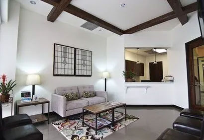 A modern living room with a high ceiling, wooden beams, and contemporary furniture.