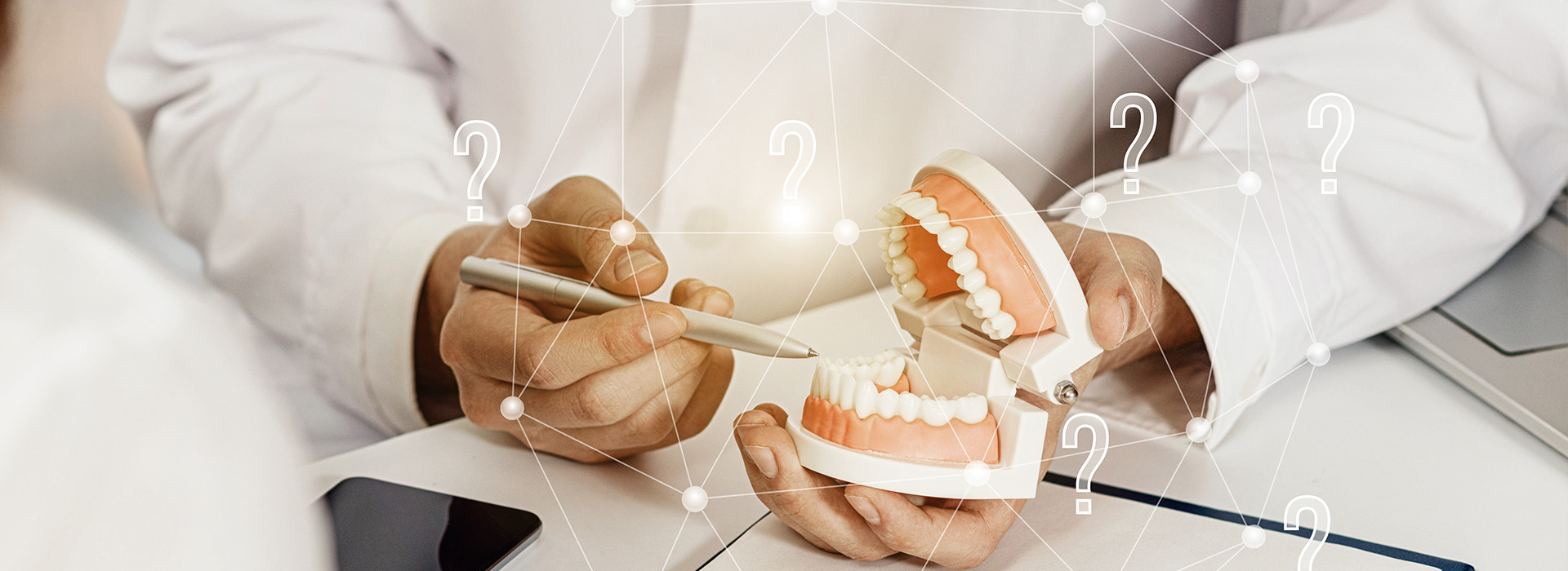 A person s hands holding dental implants with a blurred background featuring a whiteboard and a clock.