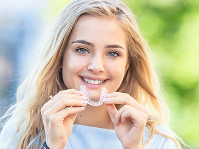Woman holding toothbrush with smile.