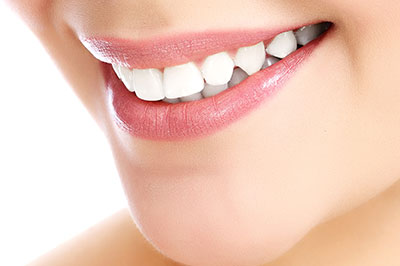 An image of a person smiling with white teeth, showcasing their smile against a neutral background.