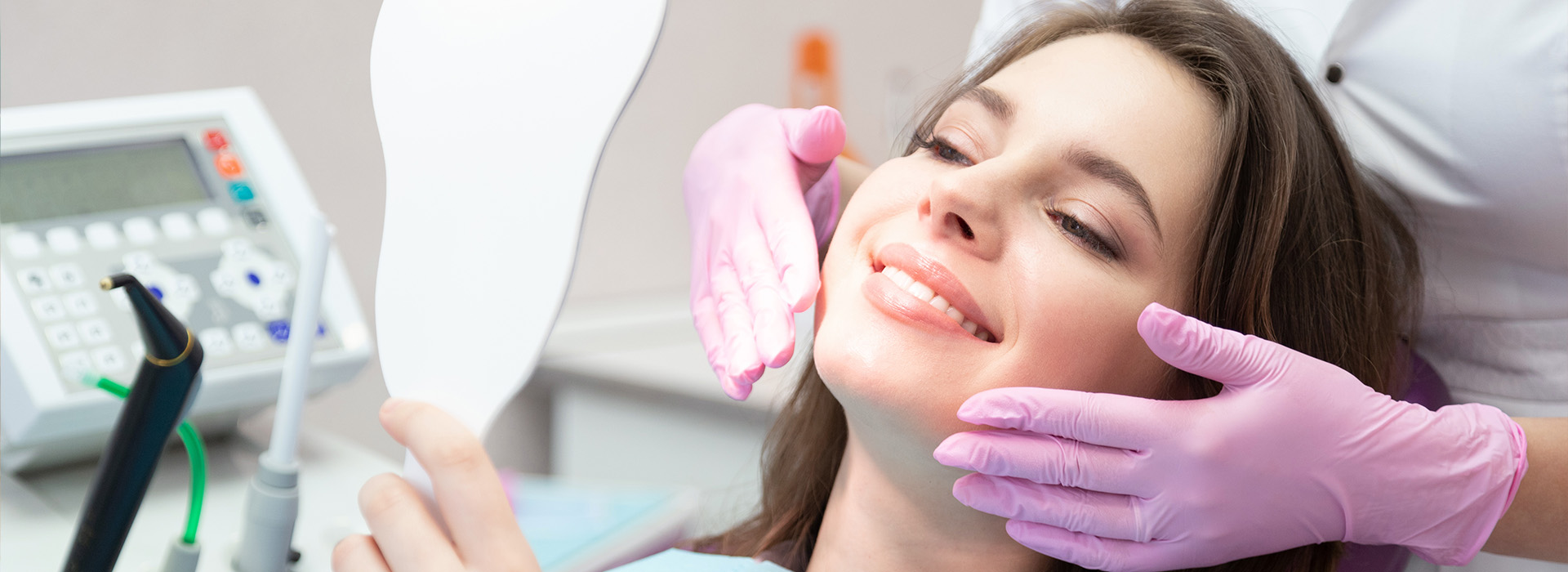A woman receiving dental care with a smile on her face, while a dental professional adjusts her mouthpiece.