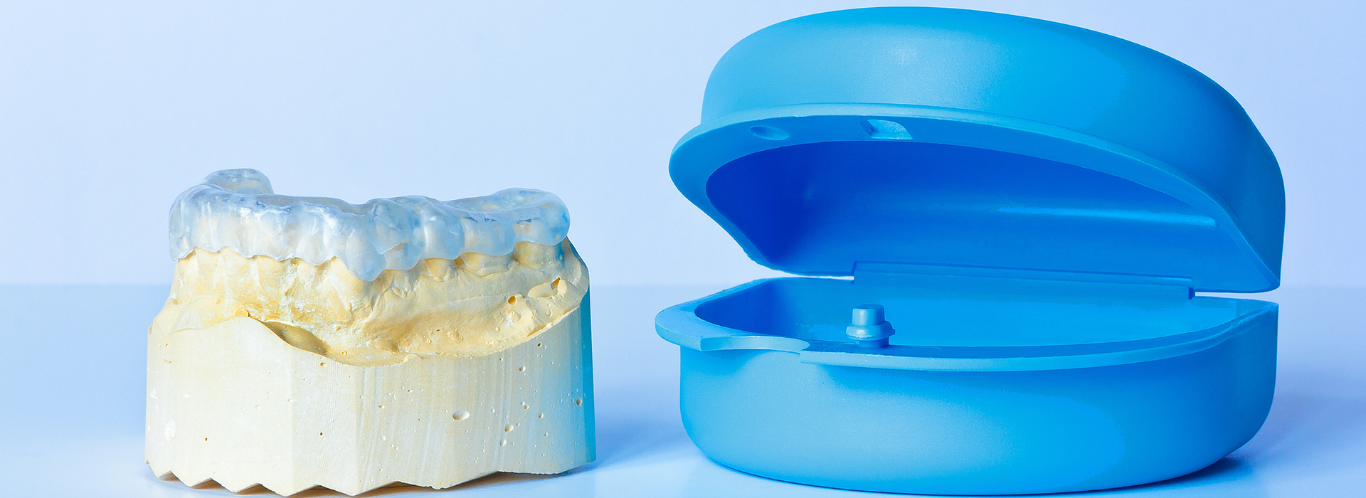 The image shows two dental implants  one with a blue cap and another without any cap, placed on a plain white background.