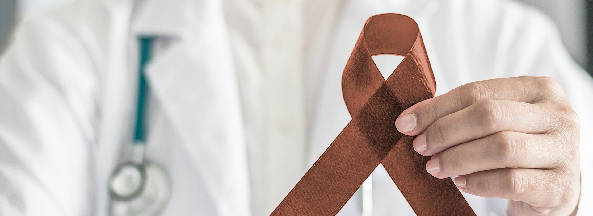 The image features a healthcare professional holding up a red ribbon with a white cross symbolizing medical aid, set against a backdrop that reads  AIDS.