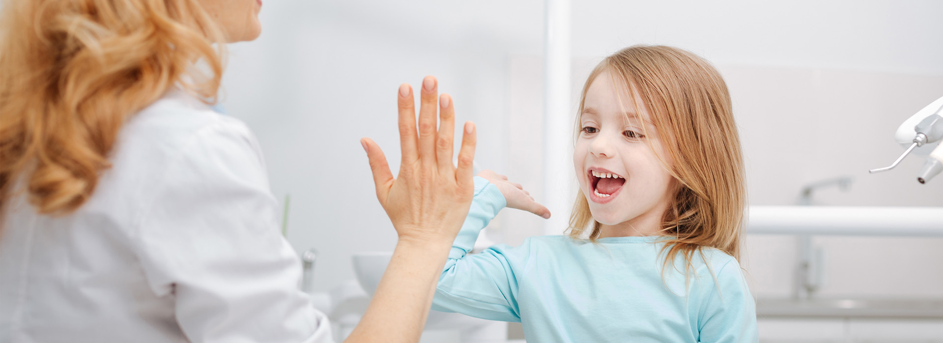 A young girl is excitedly waving her hand towards an adult woman while they are both in a bathroom.