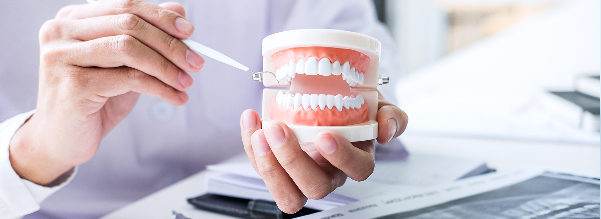 A person holding a toothbrush with toothpaste next to a cup.