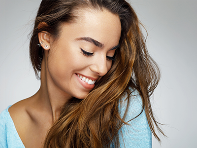The image features a woman with long hair smiling at the camera, wearing a light blue top.