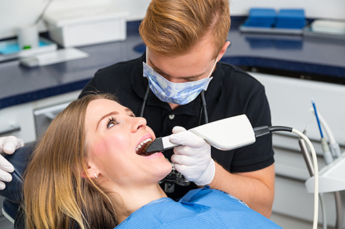 A dental hygienist using an electric toothbrush on a patient s teeth during a cleaning appointment.