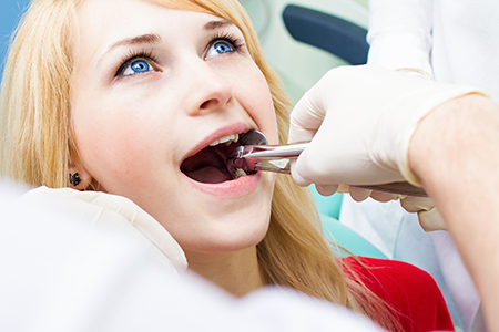 A woman receiving dental treatment, with a dentist performing the procedure and assisted by another person.
