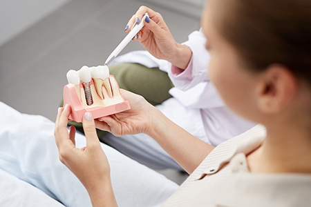 The image shows a dental professional performing an oral examination on a patient using a mirror and a tool to inspect teeth.