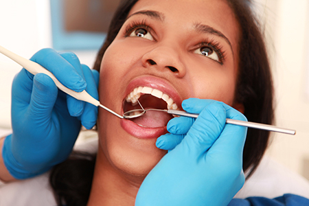 The image depicts a person receiving dental care with a dental hygienist performing the procedure.
