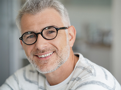 The image shows a man with glasses smiling at the camera, with two smaller images on either side of him, also featuring the same man with glasses and a similar expression.
